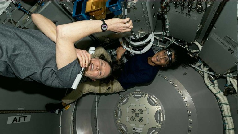 NASA astronauts Tracy C. Dyson and Suni Williams work inside the Nanoracks Bishop Airlock on the ISS, installing the ArgUS Mission-1 hardware to test its external operations in space.