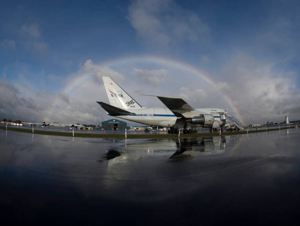 NASA's SOFIA flying observatory is framed by a rainbow following a shower as it sits on a ramp at Christchurch International Air
