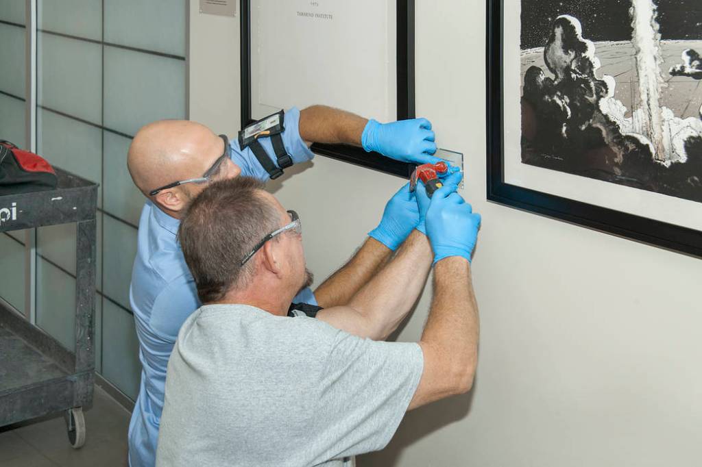 Technicians hang Robert McCall's lithographs depicting highlights of the Apollo 11 moon landing mission in 1969. 