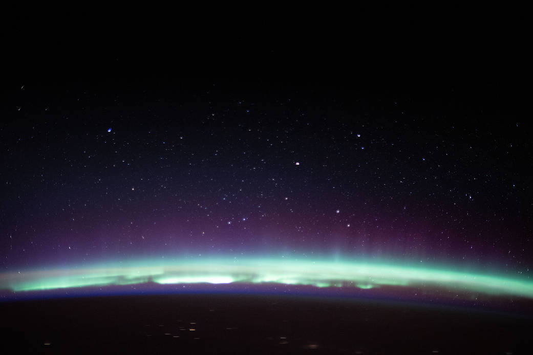 A radiant aurora crowns the Earth's horizon