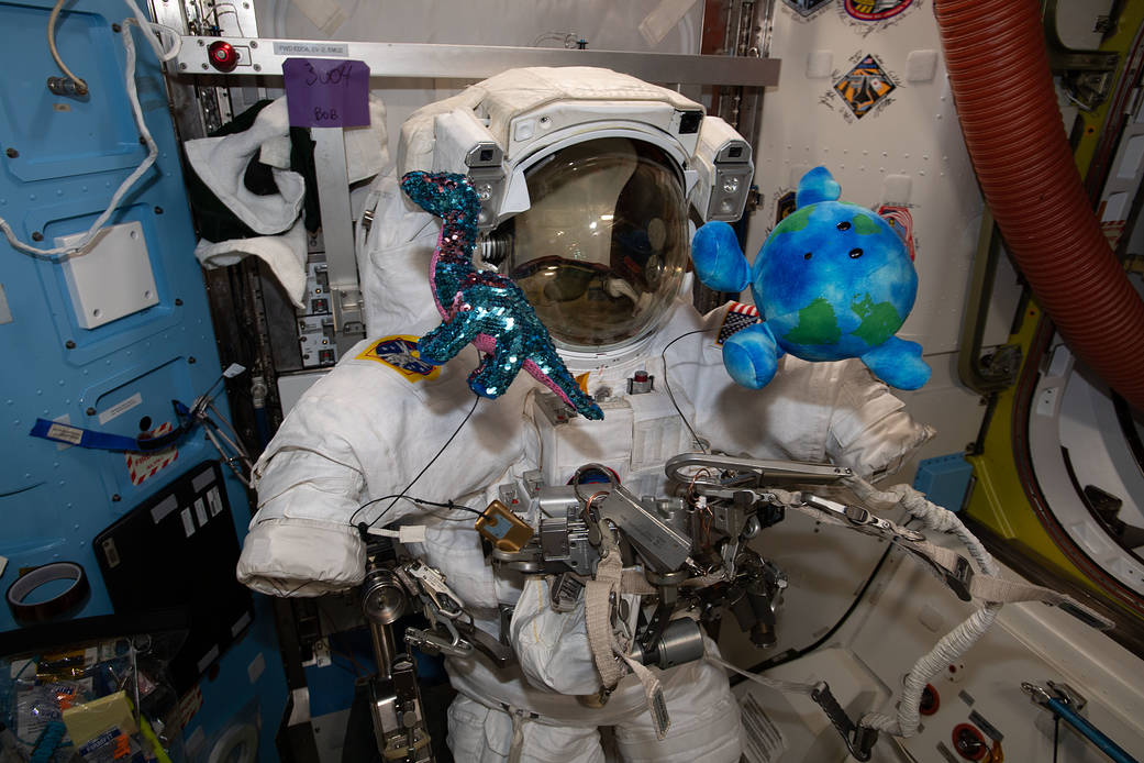 A U.S. spacesuit is pictured with plush-doll mascots