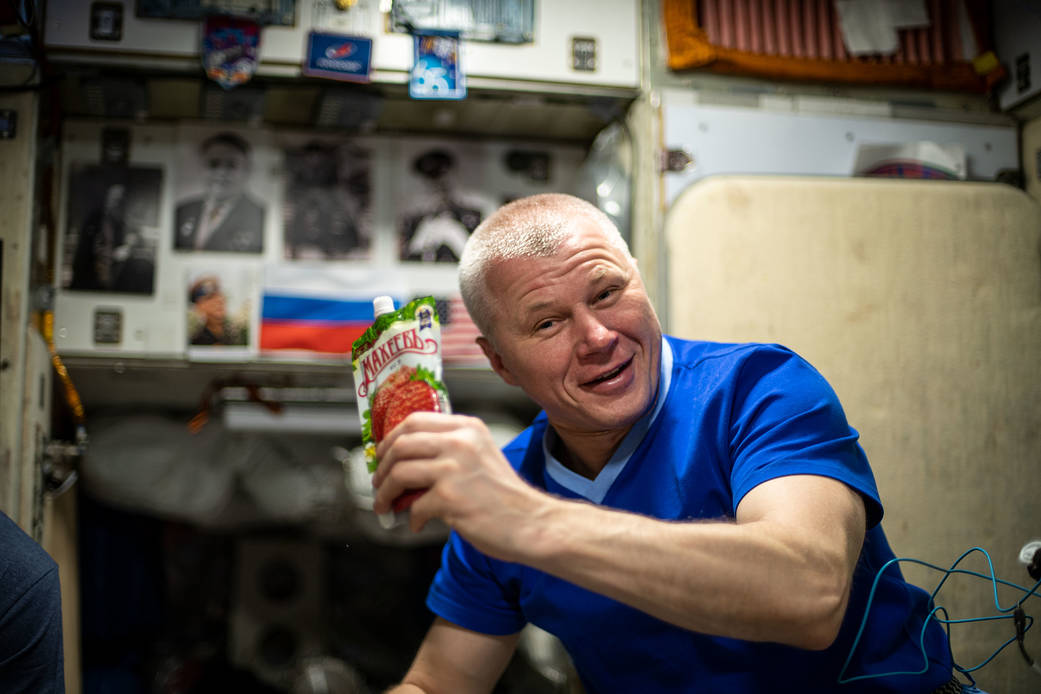 Roscosmos cosmonaut Oleg Novitskiy shows off a drink bag