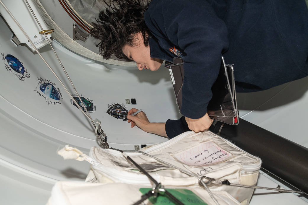 Astronaut Samantha Cristoforetti signs her name around the Crew-4 sticker