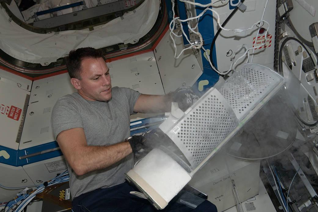 Astronaut Josh Cassada stows blood samples inside a science freezer