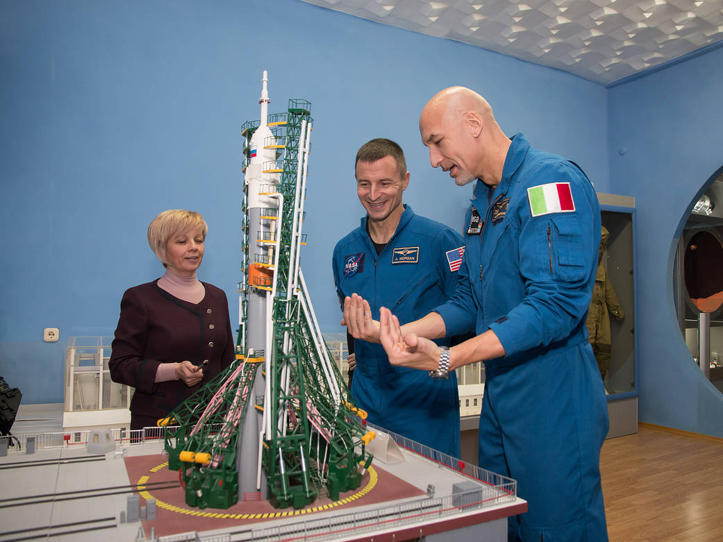 Expedition 58 backup crew members examine a model of a Soyuz rocket