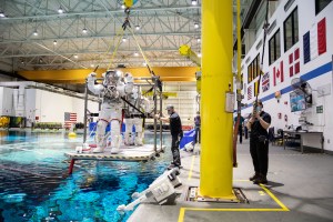 NASA astronauts Kjell Lindgren and Bob Hines are pictured suited up atop one of the cranes that is used to lower astronauts into the pool ahead of spacewalk training inside the NBL. Credit: NASA/Josh Valcarcel