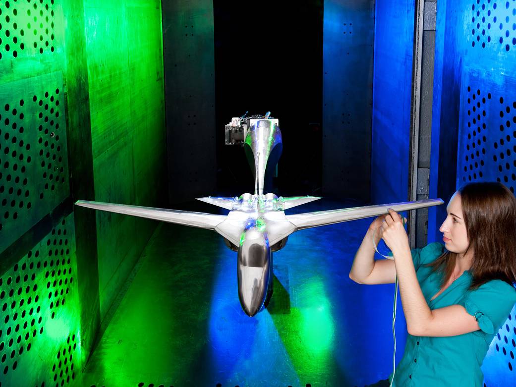 Inside the 8x6 Supersonic Wind Tunnel, a female engineer is placing trip dots on the leading edge of the wing.