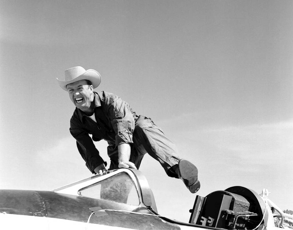 Test pilot Joe Walker in cowboy hat and boots jumping into the cockpit of an aircraft.
