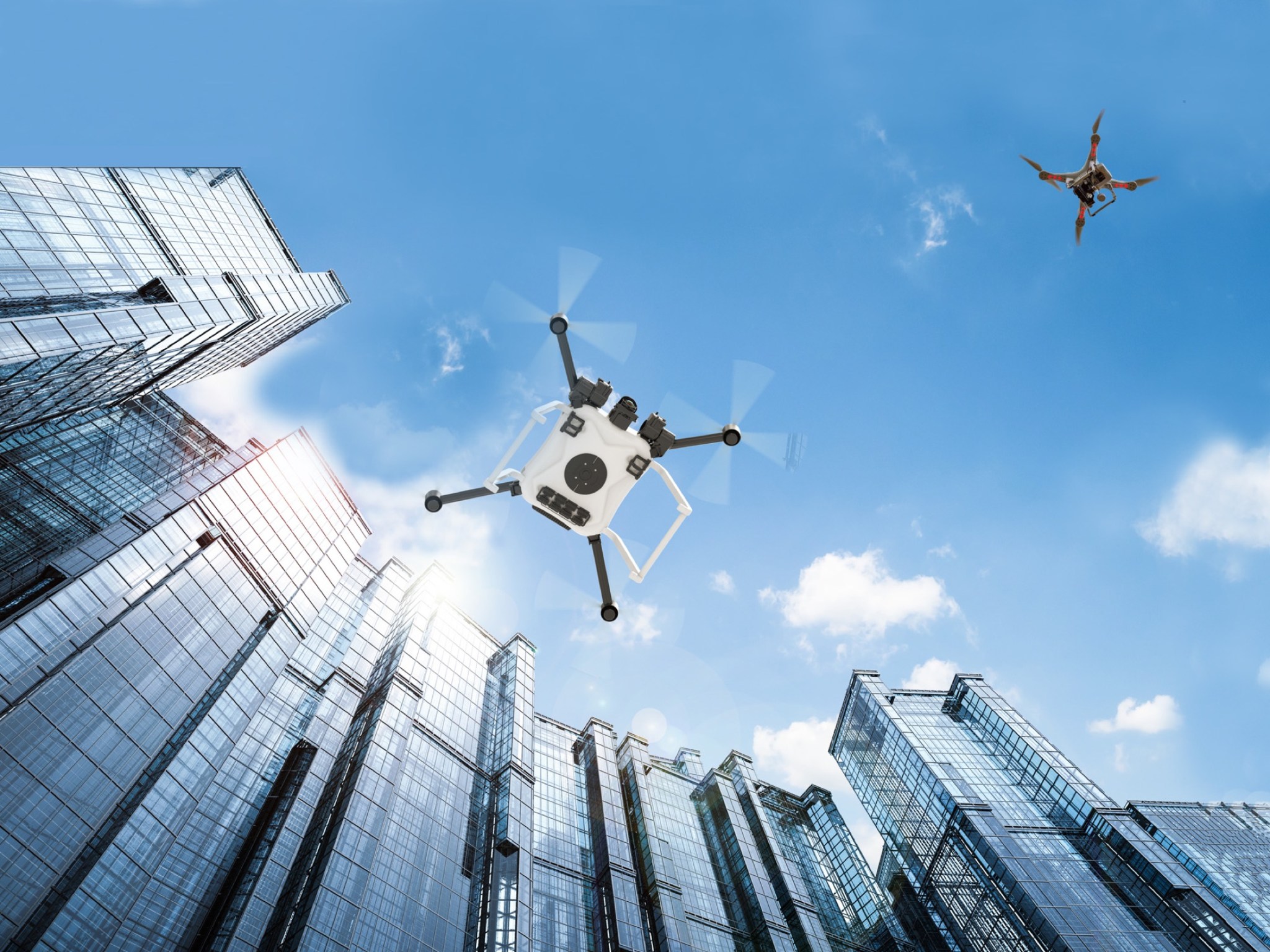 Autonomous vehicle drones in flight among city buildings.