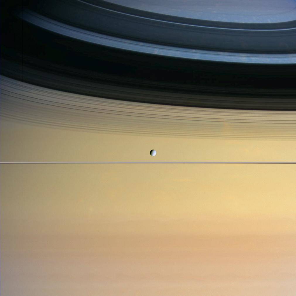 Moon Dione visible in front of large planet Saturn