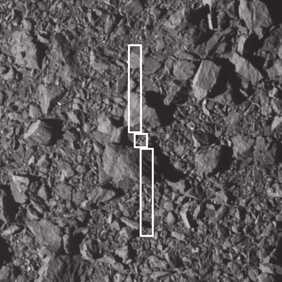 A grey rocky looking terrain has three white rectangles showing where the DART mission hit the asteroid moonlet.