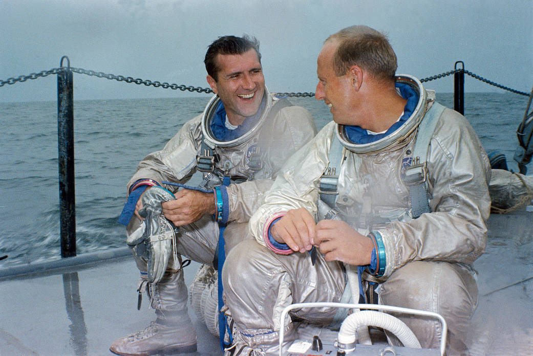 Two astronauts in spacesuits on deck of ship