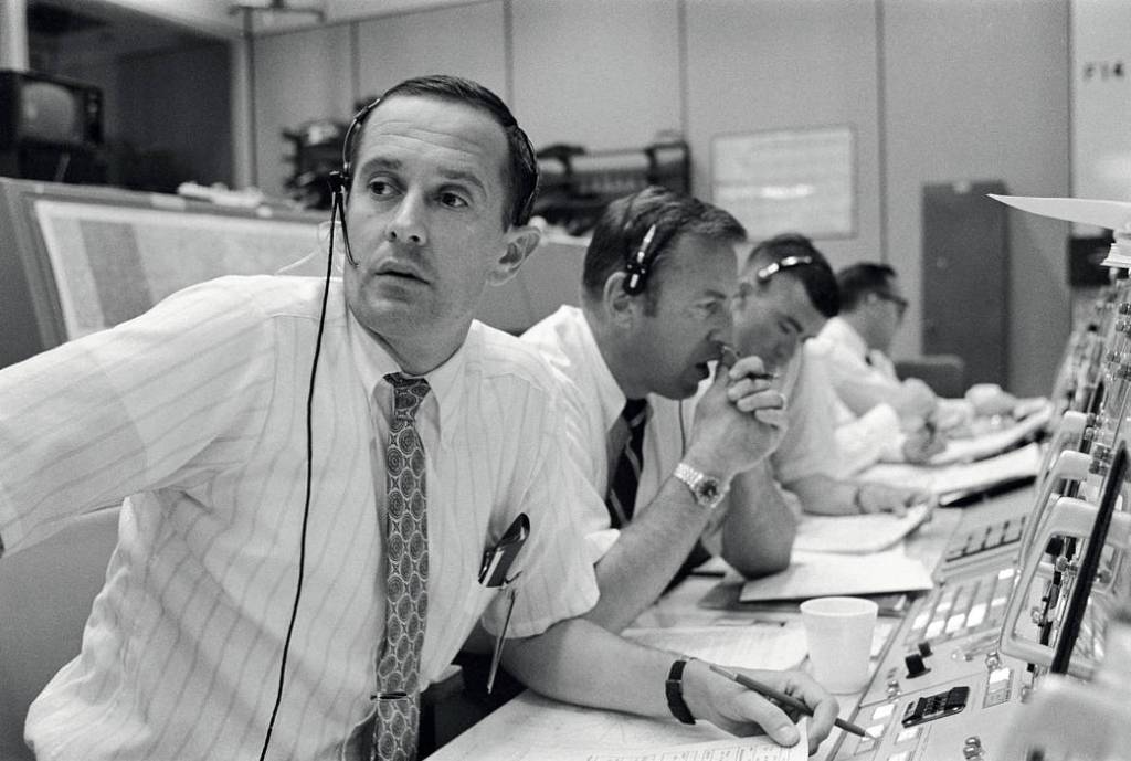 Men with headsets at control desk in Mission Control