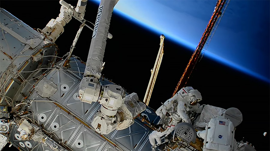 The Earth begins illuminating during an orbital sunrise as spacewalkers (lower right) Sultan Alneyadi and Stephen Bowen work outside the space station. Credit: NASA TV