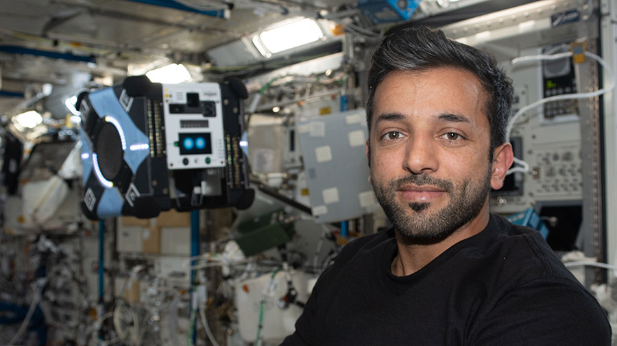 UAE (United Arab Emirates) astronaut Sultan Alneyadi poses with a free-flying AstroBee robotic helper inside the space station's Kibo laboratory module.