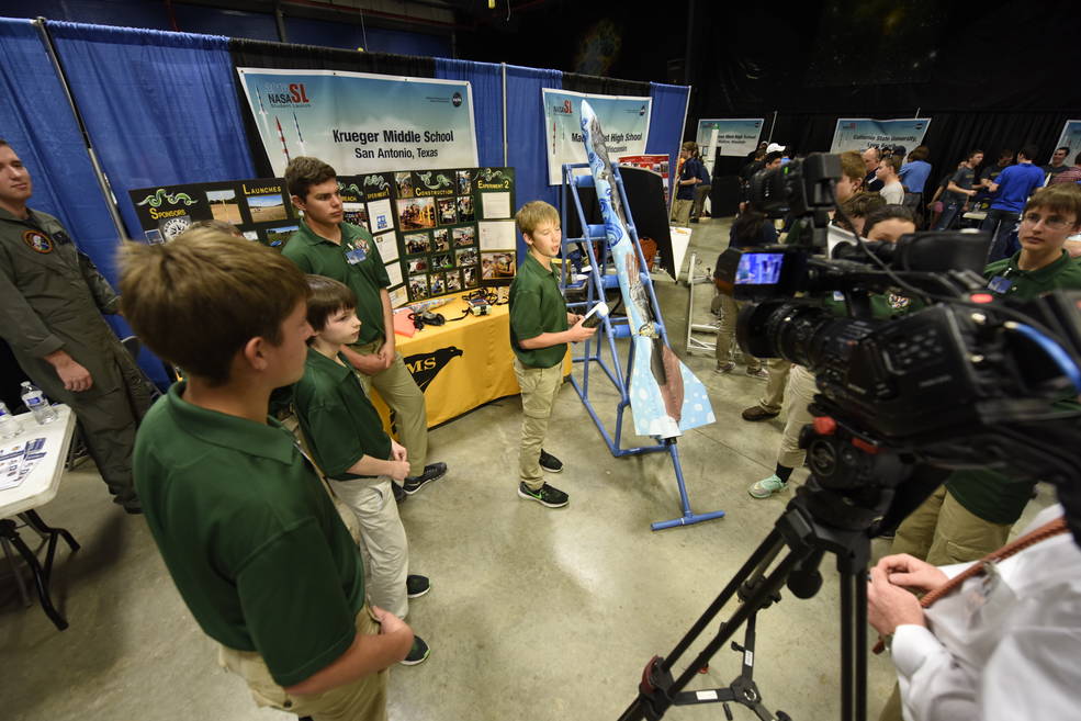 Students stand beside the rocket they created at an event in 2019.