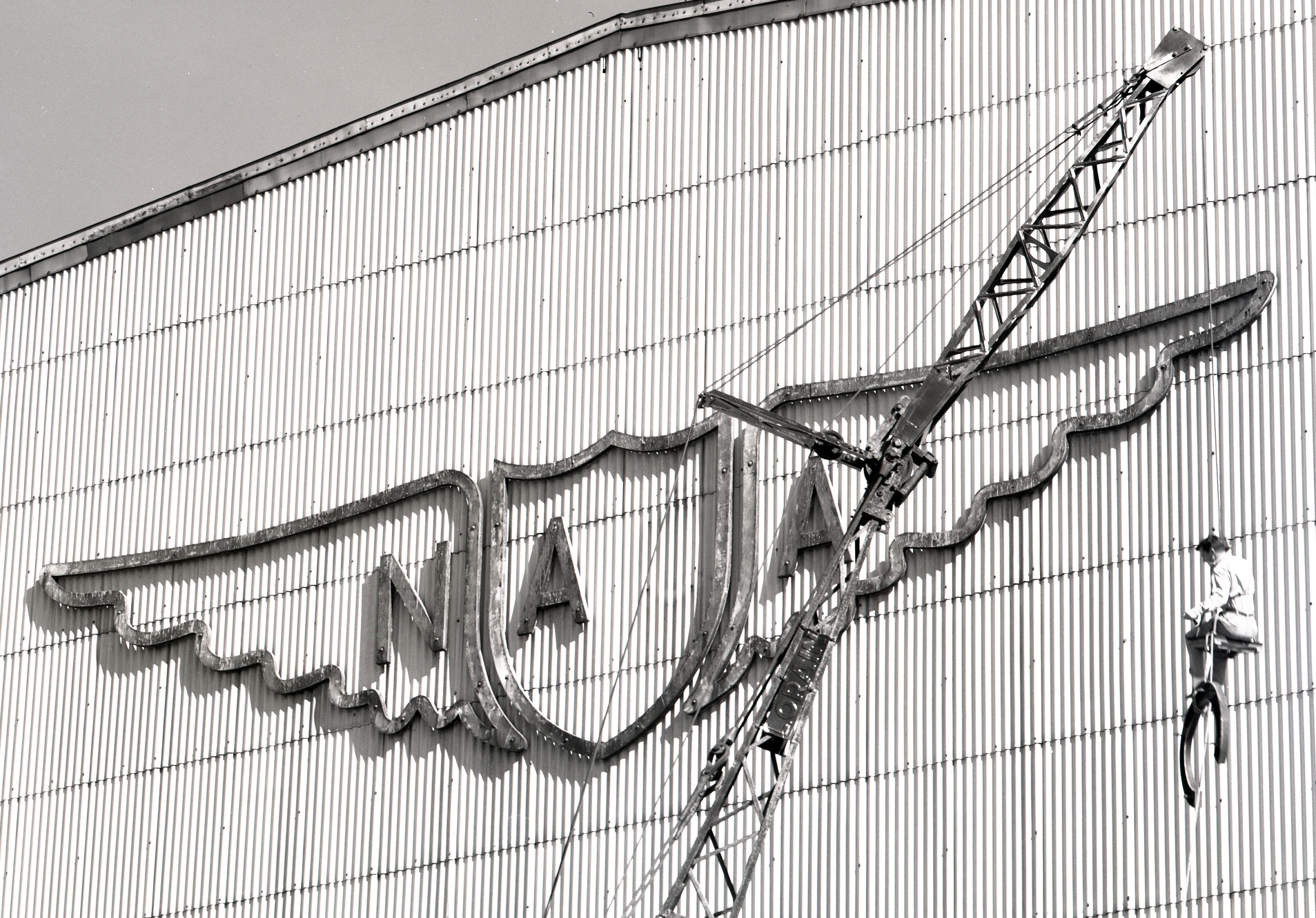 Man suspended by crane removing sign.