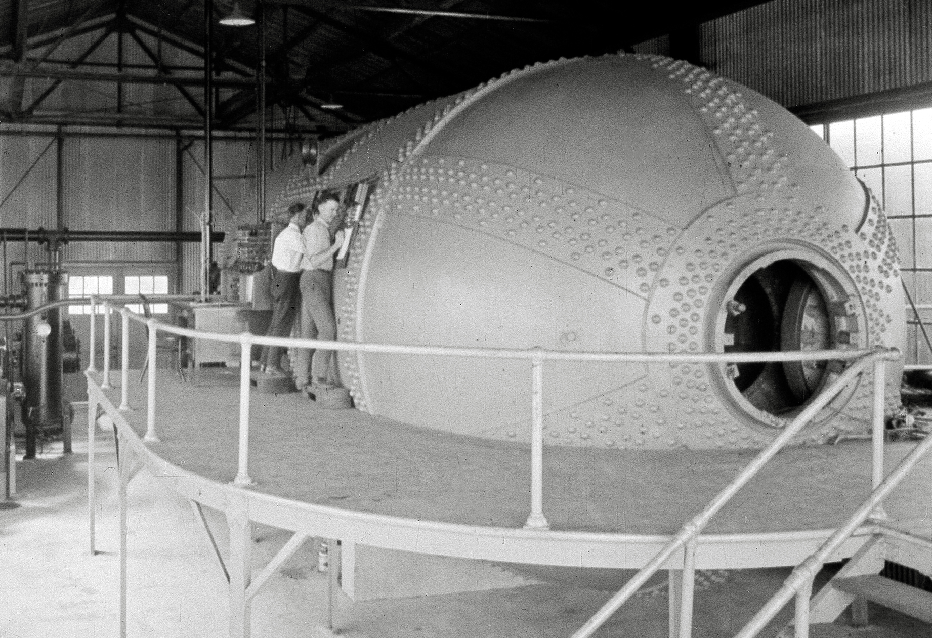 Men looking into large steel tank.