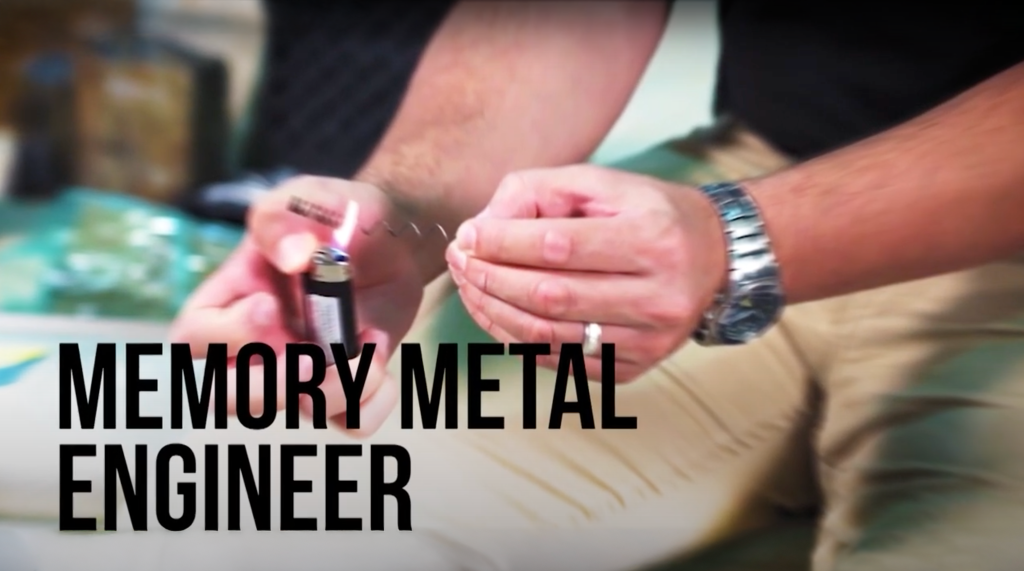 Screen shot from the Memory Metal Engineer, Surprisingly STEM Series, showing someone holding a lighter and putting fire on a metal spring.