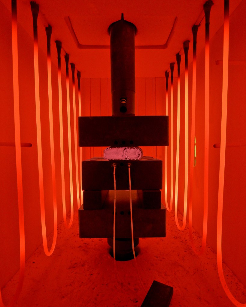 Test hardware pressed in the middle of a chamber with glowing coils.