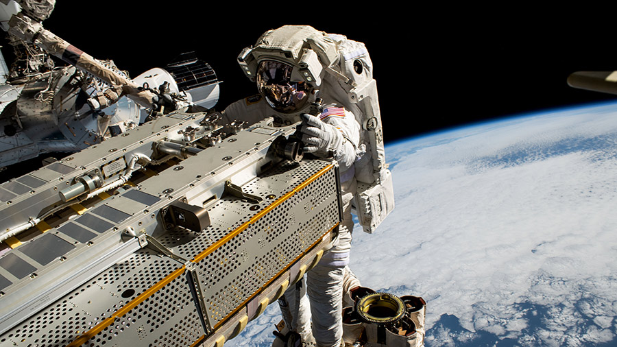 NASA astronaut Woody Hoburg rides the Canadarm2 robotic arm while maneuvering a roll-out solar array during a spacewalk on June 9, 2023, 257 miles above the Pacific Ocean.