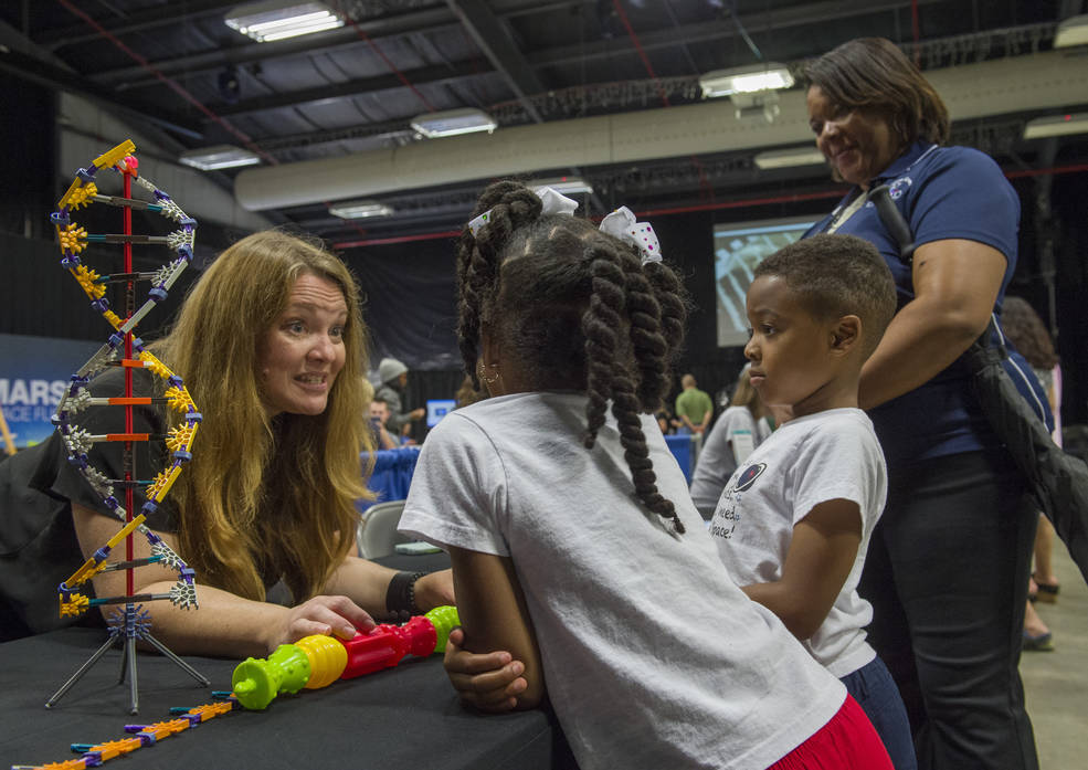 Kids listen to a woman talk about NASA and Science at take you kid to work day.