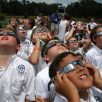 A group of Mississippi students look up at the solar eclipse with their protective glasses