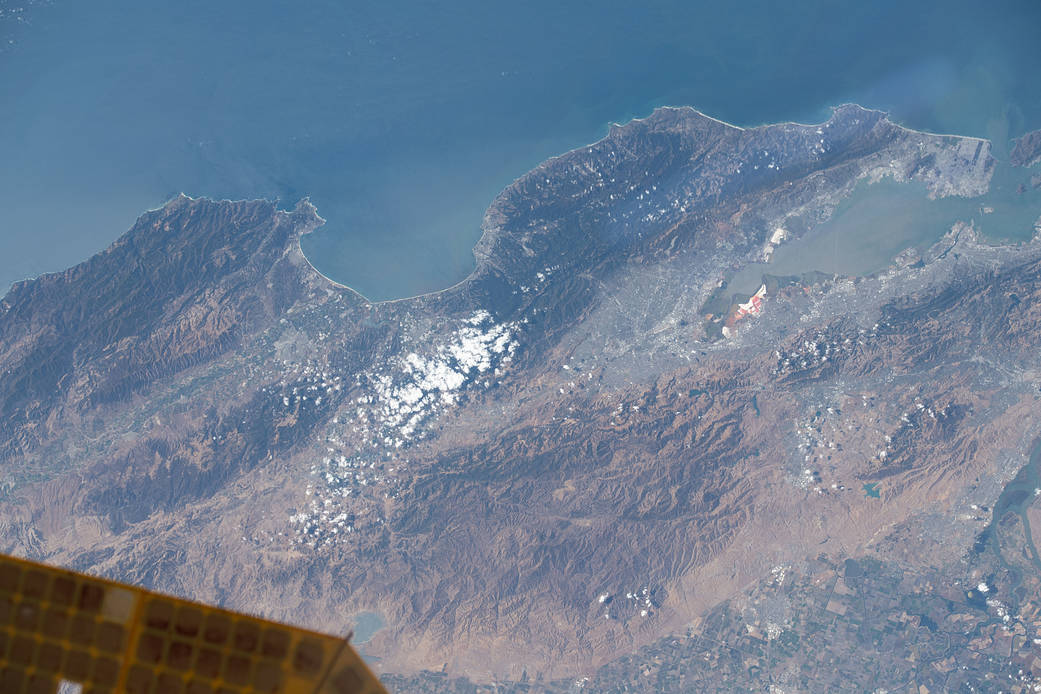 View from the International Space Station of central California including the Pinnacles National Park, with the edge of one of the station's solar arrays visible in the lower left corner.