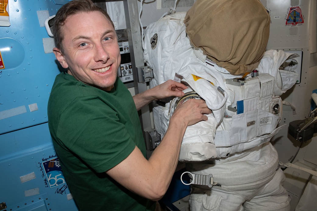 NASA astronaut Woody Hoburg prepares a spacesuit for a spacewalk