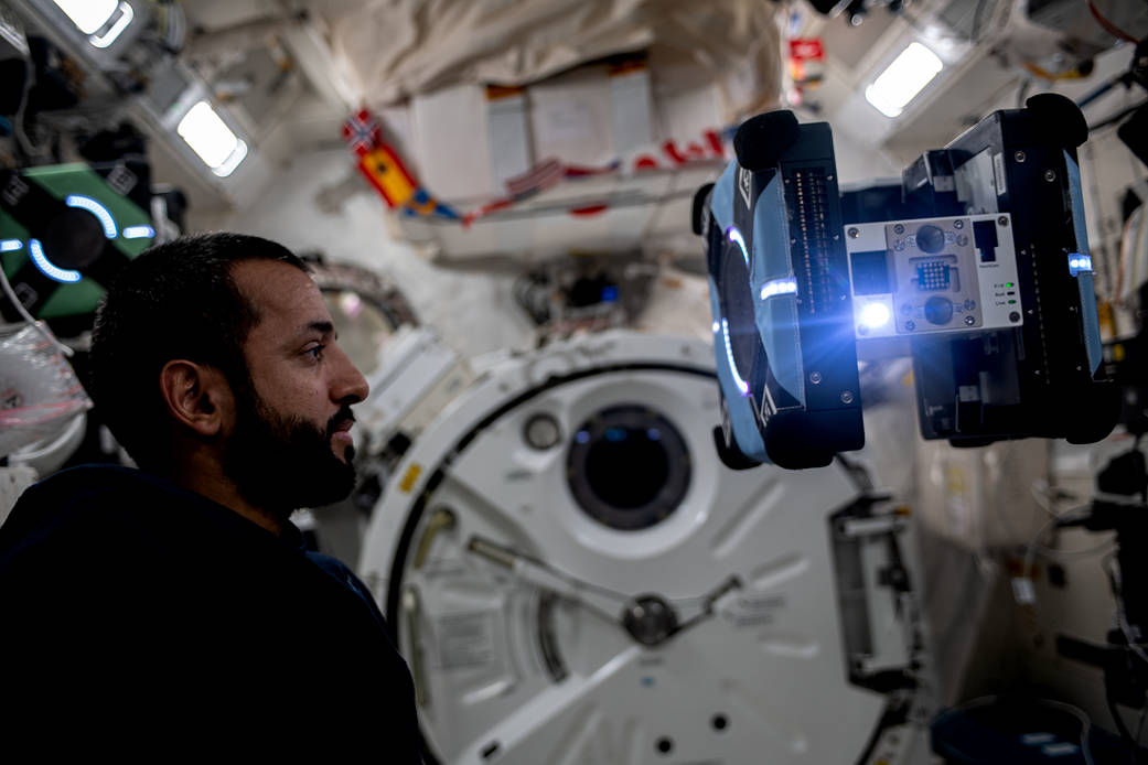 Astronaut Sultan Alneyadi observes a free-flying Astrobee robotic assistant