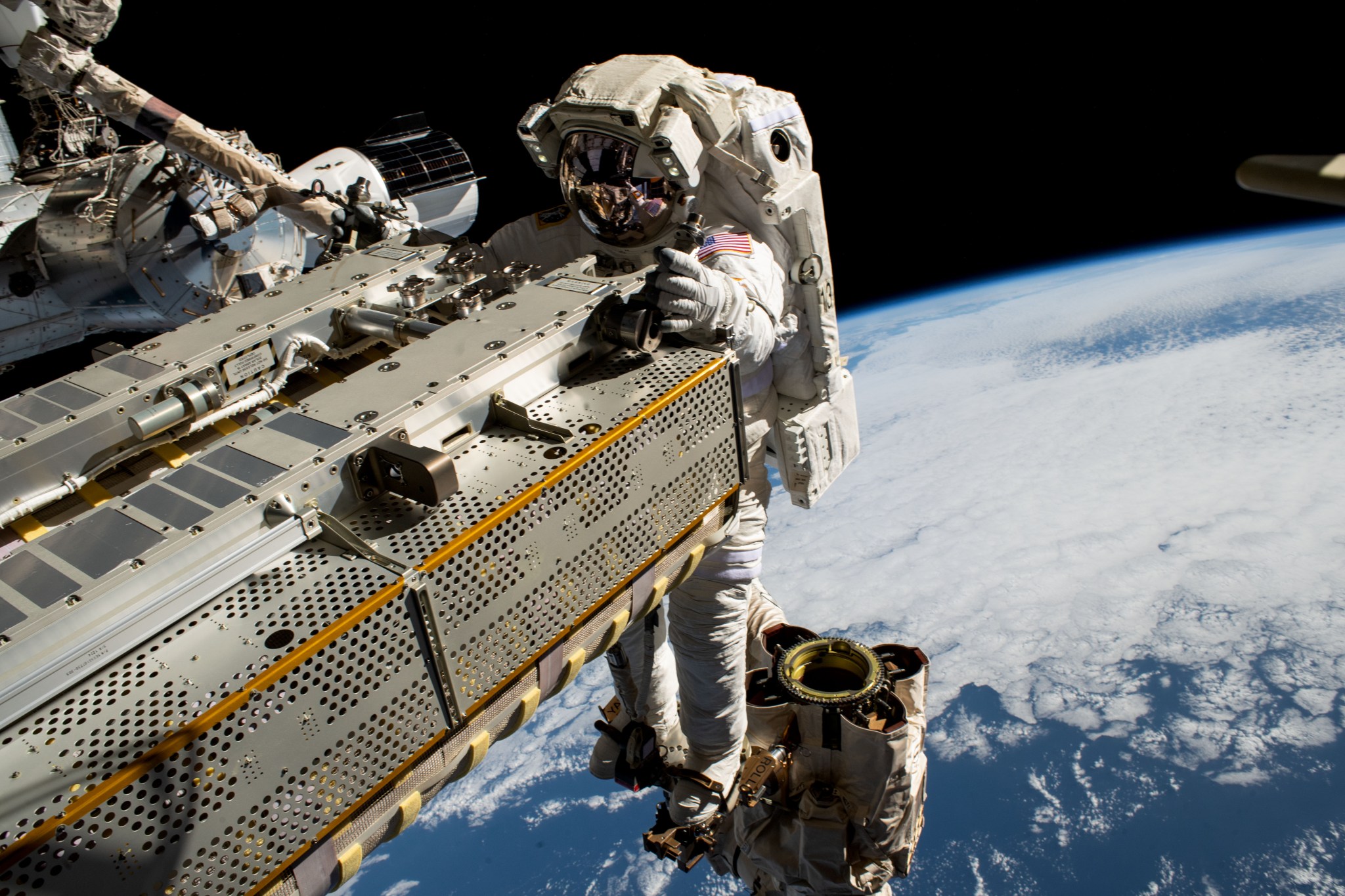 宇航员伍迪·霍伯格（Woody Hoburg）在太空行走期间驾驶Canadarm2机器人手臂操纵展开式太阳能电池阵列。