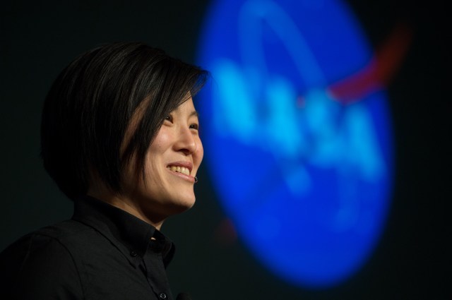 Tina Lai站在美国国家航空航天局（NASA）亮起的徽章前，对一群看不见的人讲话