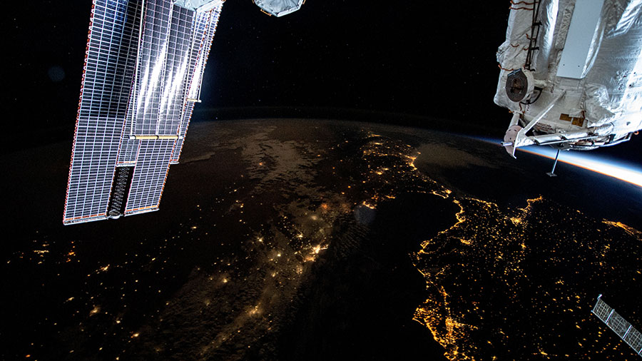 This nighttime photograph shows the Mediterranean Sea ringed by the coastal city lights of Morocco and Algeria on the African side and Spain on the European side.