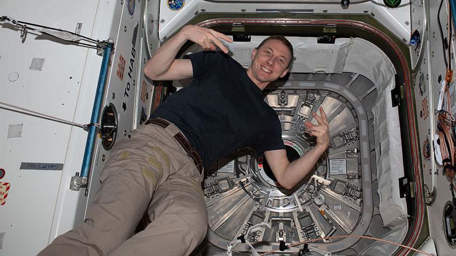 Astronaut Woody Hoburg poses for a portrait inside the vestibule that separates the Unity module from the Cygnus space freighter's hatch.