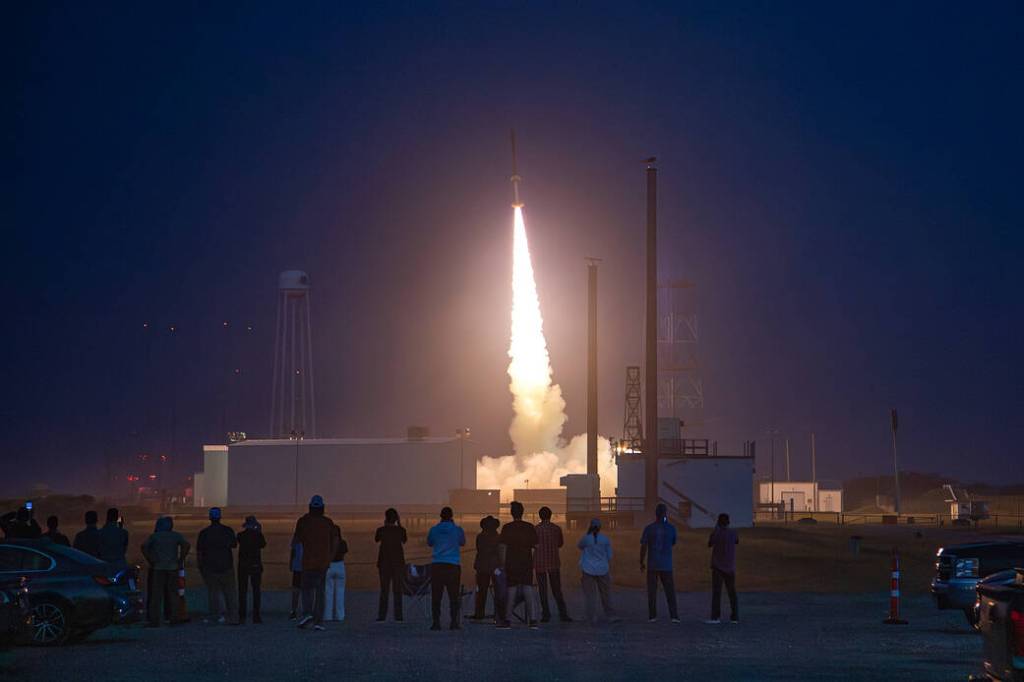 Students watch a sounding rocket launch at sunrise.