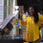 Roman Space Telescope Technical Photographer Jolearra Tshiteya standing next to a display.