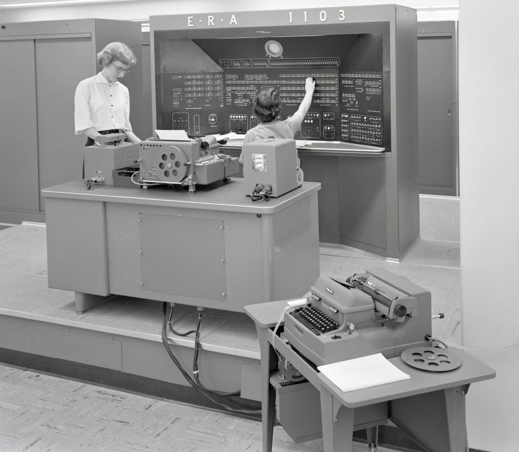 Two woman working with large computer.