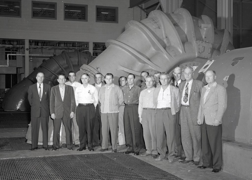 Group of men standing in front of equipment.