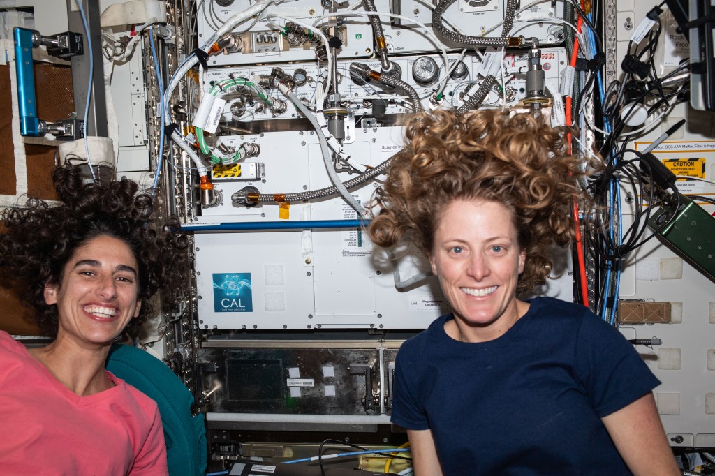 Expedition 70 Flight Engineers (from left) Jasmin Moghbeli and Loral O'Hara, both from NASA, pose for a portrait in front of the International Space Station's Cold Atom Lab. The physics research device observes the quantum behavior of atoms chilled to about one ten billionth of a degree above absolute zero -- much colder than the average temperature of deep space.