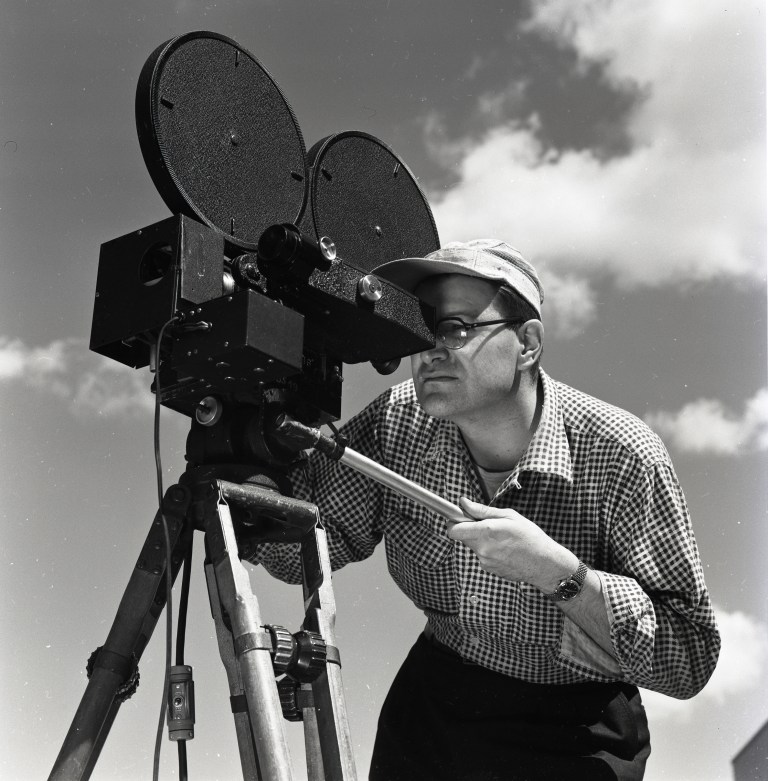 Man operating camera on tripod.