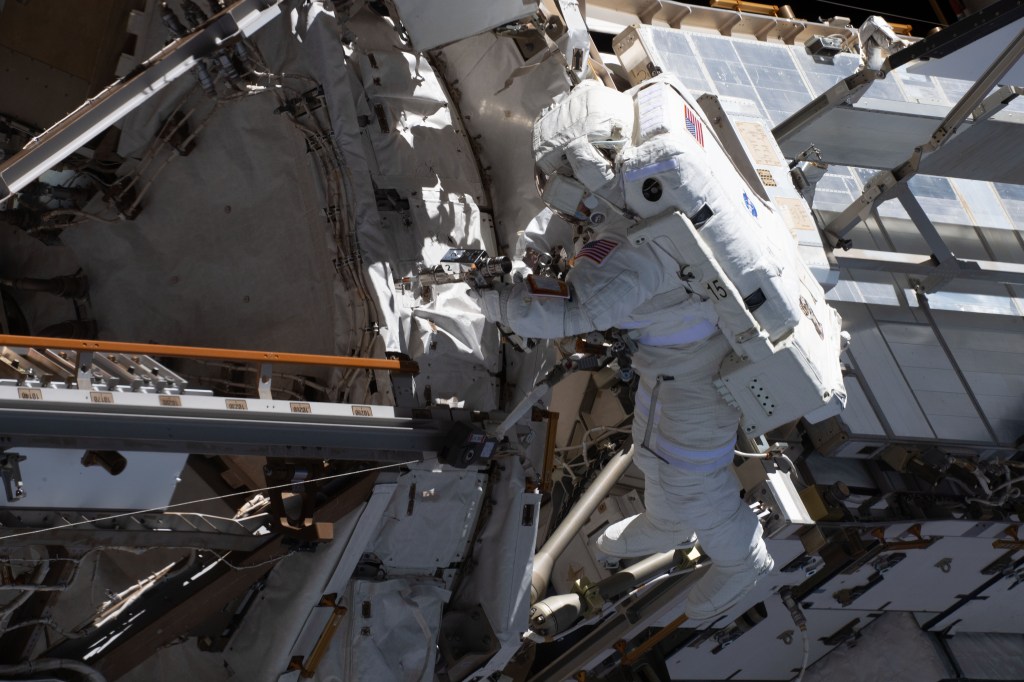 NASA astronaut and Expedition 70 Flight Engineer Loral O'Hara is pictured (center) tethered to the International Space Station's port truss structure during a spacewalk to replace one of the 12 trundle bearing assemblies on the port solar alpha rotary joint, which allows the arrays to track the Sun and generate electricity to power the station.