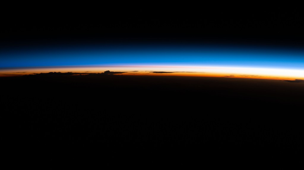 An orbital sunrise illuminate's Earth's atmosphere silhouetting clouds as the International Space Station soared 264 miles above the Paraguay-Brazil border in South America.