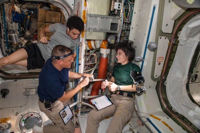 (Clockwise from right) Expedition 67 Flight Engineers Samantha Cristoforetti of ESA (European Space Agency), and Bob Hines and Jessica Watkins, both from NASA, check thermal system components inside the International Space Station's Unity module.