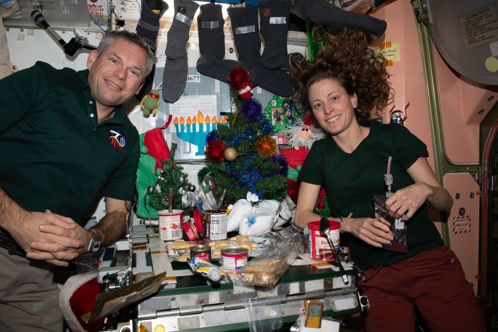 Expedition 70 Commander Andreas Mogensen from ESA (European Space Agency) and NASA Flight Engineer Loral O'Hara are pictured inside the International Space Station's Unity module enjoying a Christmas Day meal.