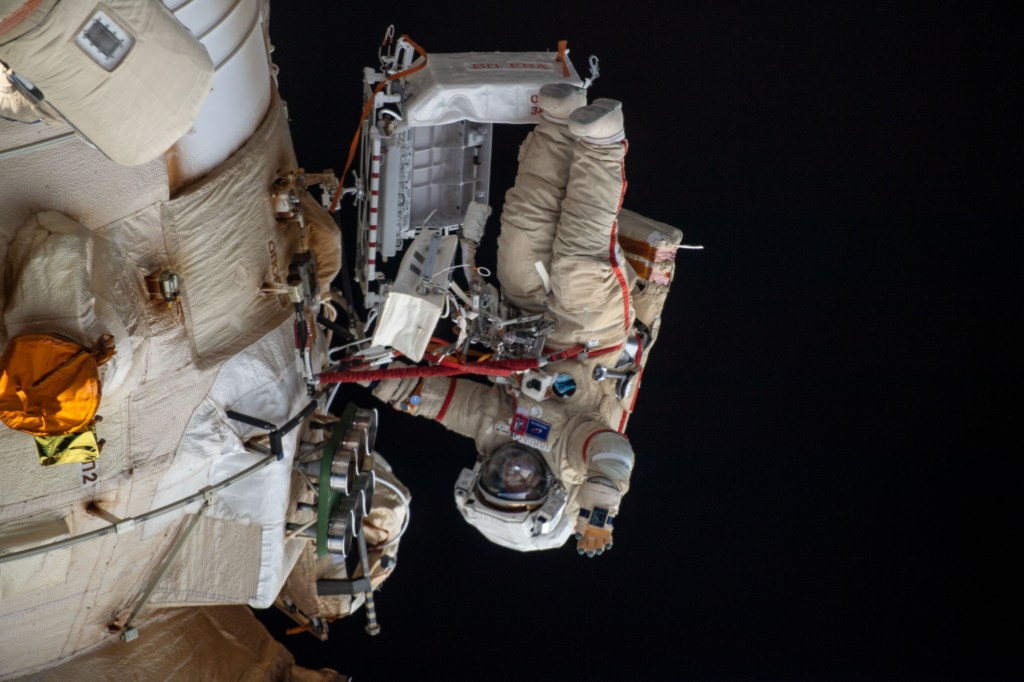 Cosmonaut Oleg Artemyev waves to the camera while working outside the Nauka multipurpose laboratory module during a spacewalk that lasted for six hours and 37 minutes to outfit Nauka and configure the European robotic arm on the International Space Station's Russian segment.