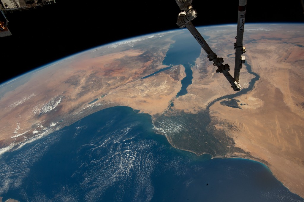 The Canadarm2 robotic arm extends from the top right foreground, with the Nile Delta and the Red Sea, situated in the Arabian Peninsula, pictured from the International Space Station as it orbited 257 miles above the Mediterranean Sea.