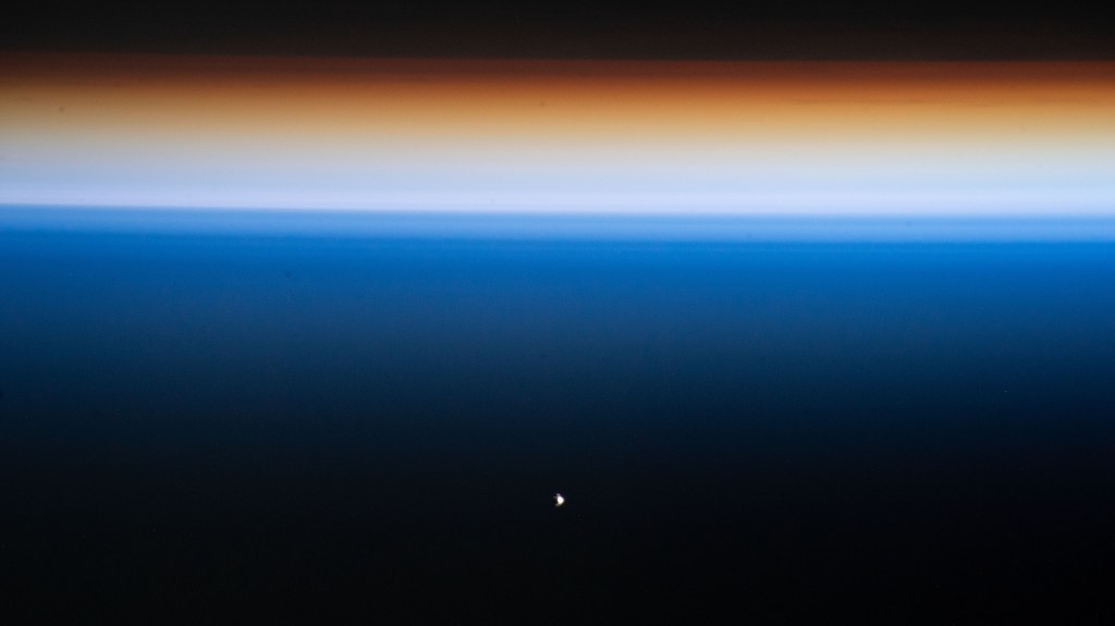 The SpaceX Dragon Endeavour crew ship (white dot at lower center) carrying four Axiom Mission 1 astronauts approaches the International Space Station during an orbital sunset less than a day after launching from NASA's Kennedy Space Center in Florida. Both spacecraft were orbiting 261 miles above the Philippine Sea near the U.S. island territory of Guam.