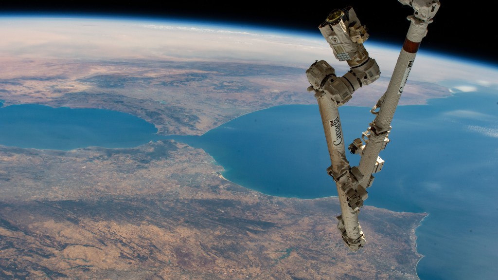 The Canadarm2 robotic arm extends from the International Space Station, orbiting 259 miles above the northern coast of Spain, in this photograph of the Strait of Gibraltar which separates the Atlantic Ocean (right) from the Mediterranean Sea and the European nation of Spain (bottom) from the African country of Morocco.