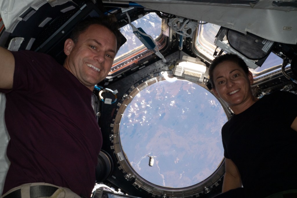 iss068e021368 (Nov. 9, 2022) --- Expedition 68 Flight Engineers Josh Cassada and Nicole Mann, both NASA astronauts, are pictured inside the cupola, the International Space Station's "window to the world." Outside the cupola, and 264 miles above southwestern Australia, Northrop Grumman's Cygnus space freighter can be seen approaching the orbiting lab carrying about 8,200 pounds of new science experiments, food, fuel, and supplies to replenish the seven-member crew. Credit: Josh Cassada/NASA