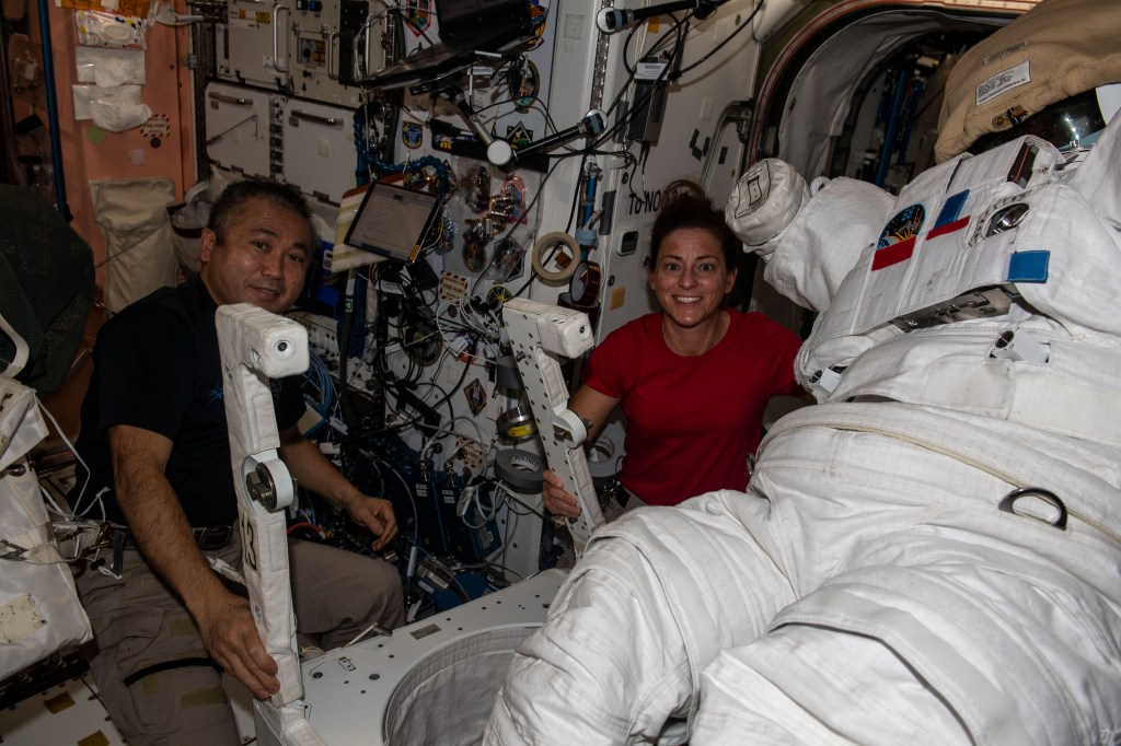 iss068e020596 (Nov. 3, 2022) --- Expedition 68 Flight Engineers Koichi Wakata of the Japan Aerospace Exploration Agency (JAXA) and Nicole Mann of NASA pose together while working on an Extravehicular Mobility Unit (EMU), also known as a spacesuit, inside the Unity module just outside the Quest airlock where spacewalks are staged with astronauts wearing the EMUs.